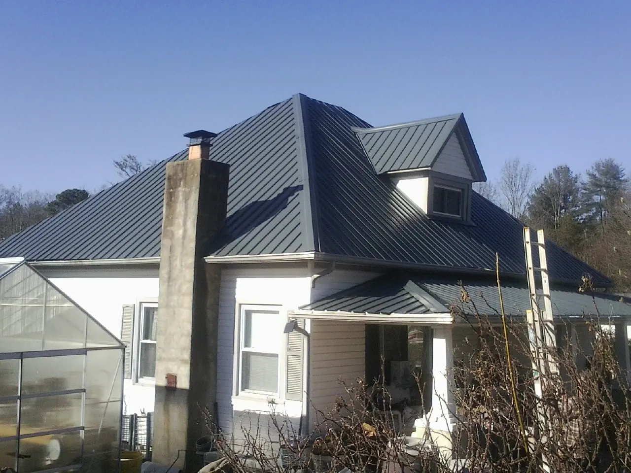 Dark blue standing seam metal roof on a white farmhouse with dormer — Slate & Tile Roof Repair by Roofing Brothers in Soddy Daisy