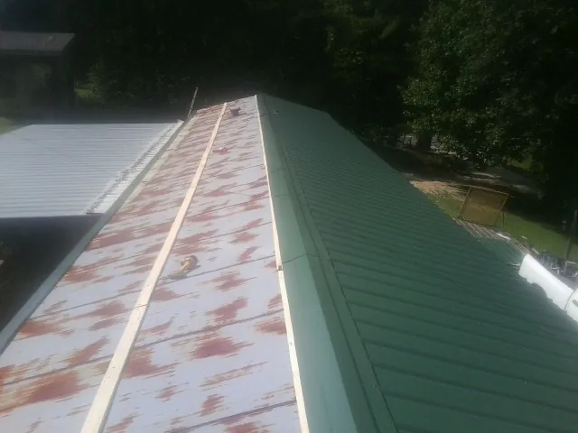 Old rusted panels beside newly installed green metal roofing — Wind Damage Roof Repair by Roofing Brothers in Soddy Daisy