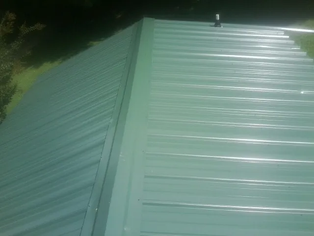 New green metal panels meeting at the ridge of a roof — Flat Roof Repair work by our crew in Soddy Daisy