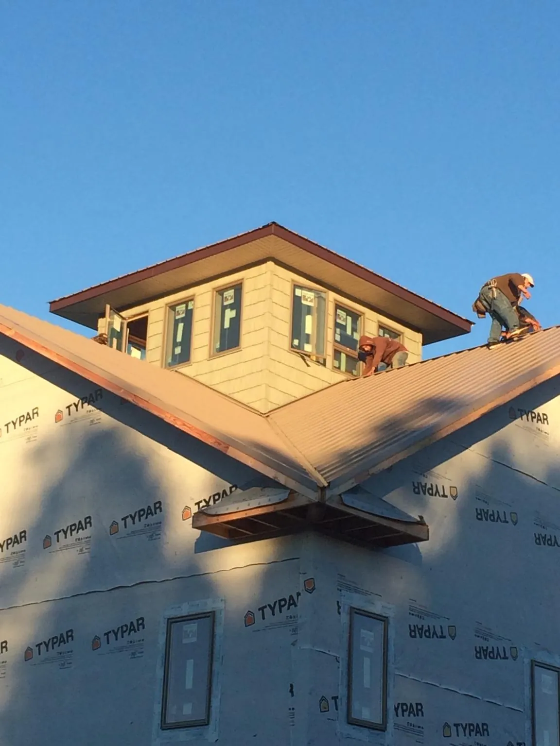 Roofers working around a rooftop cupola on a new metal roof at sunset — Roof Waterproofing in Soddy Daisy by Roofing Brothers